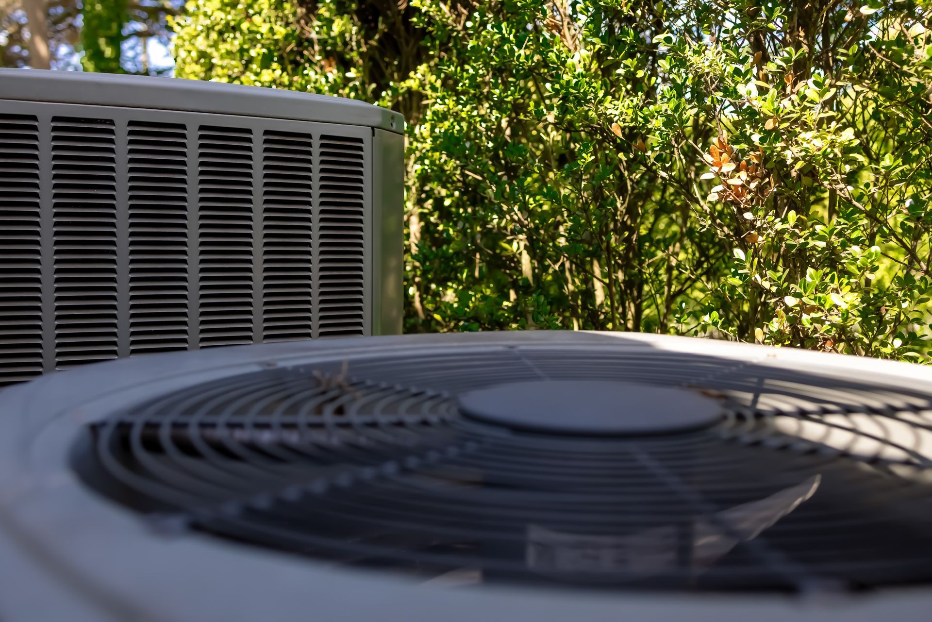 Outdoor air conditioning units with a blurred green background.