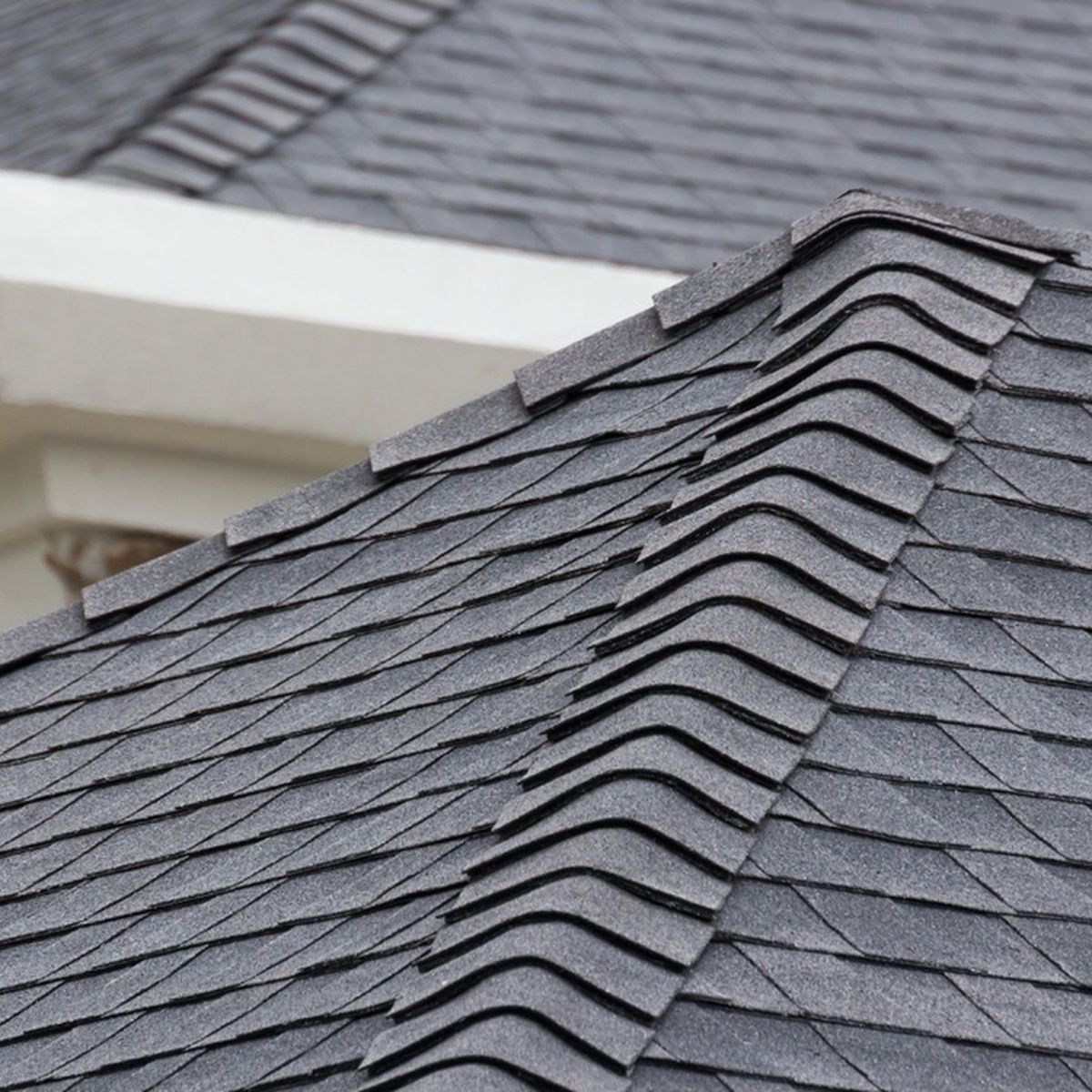 Dark gray asphalt shingle roof with a sloped ridge and vent detail