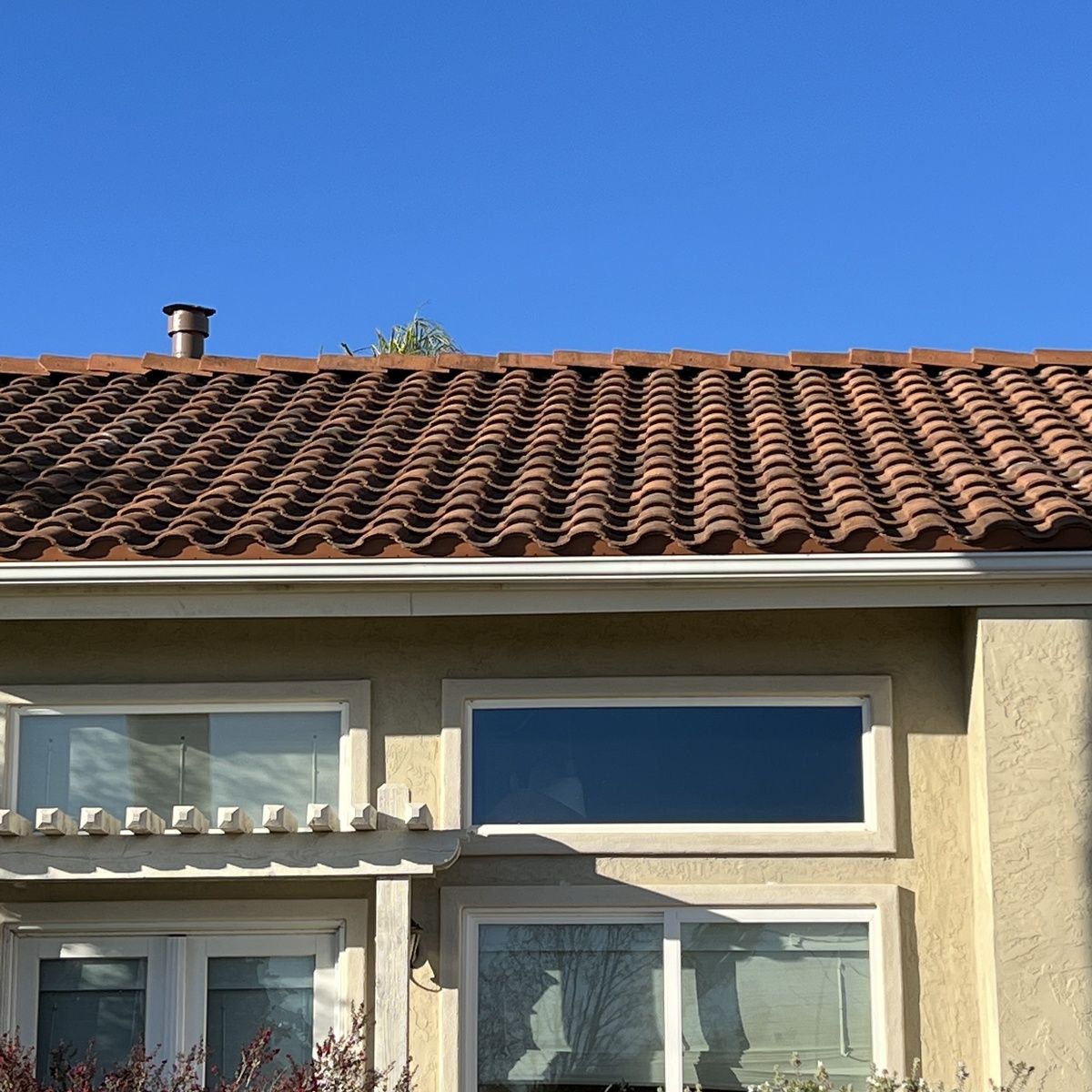 House facade with terracotta tile roof and blue sky above