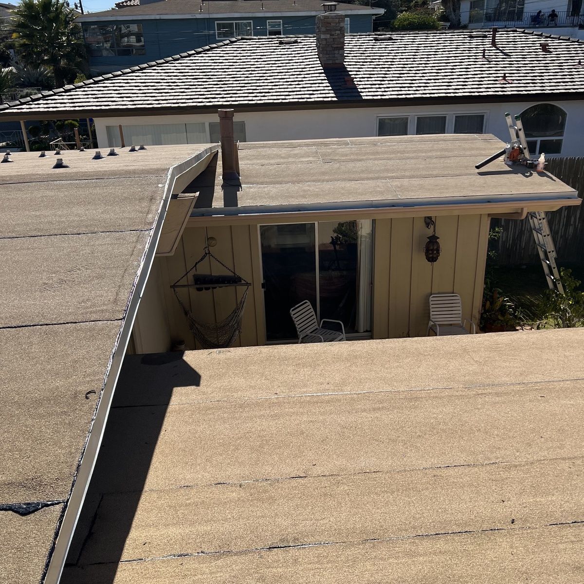 Flat tan rooftop with a central chimney and a person working near the right edge.