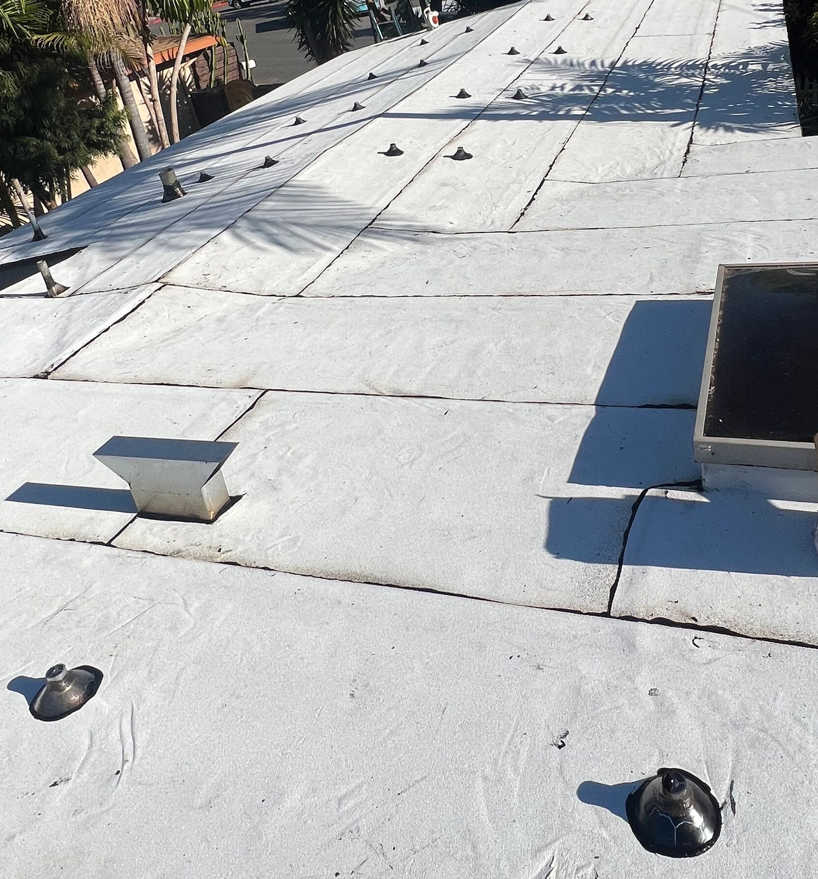 Flat white rooftop with vents and skylights in bright sunlight.