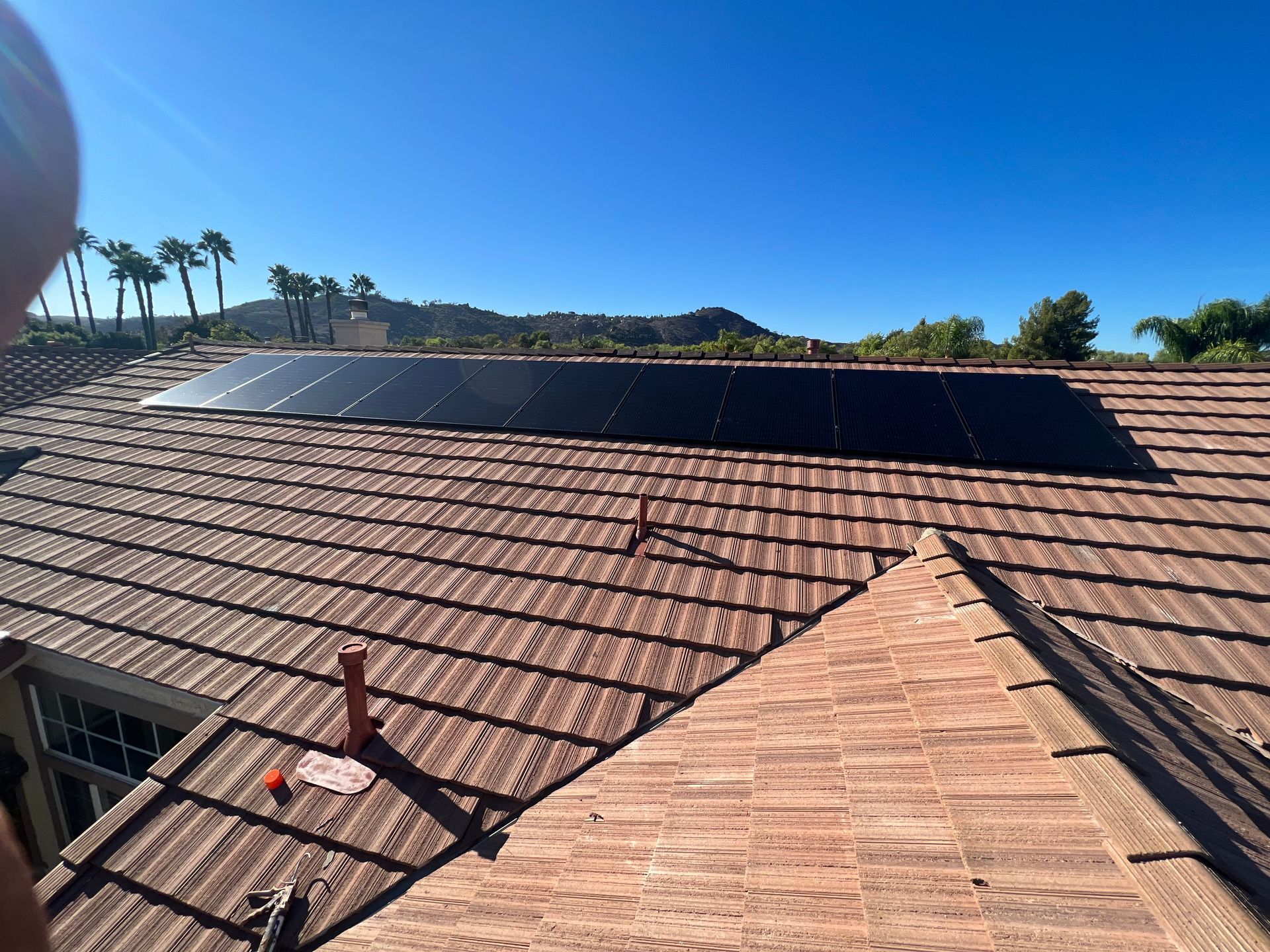 Solar panels on a shingle roof under a clear blue sky.