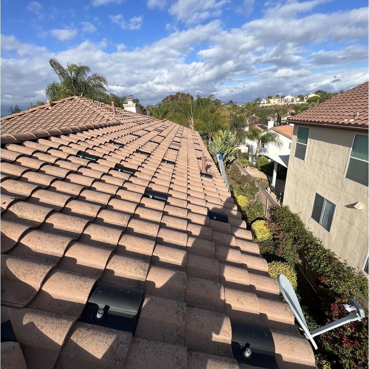 Terracotta-tiled rooftop overlooking a suburban neighborhood under a partly cloudy sky