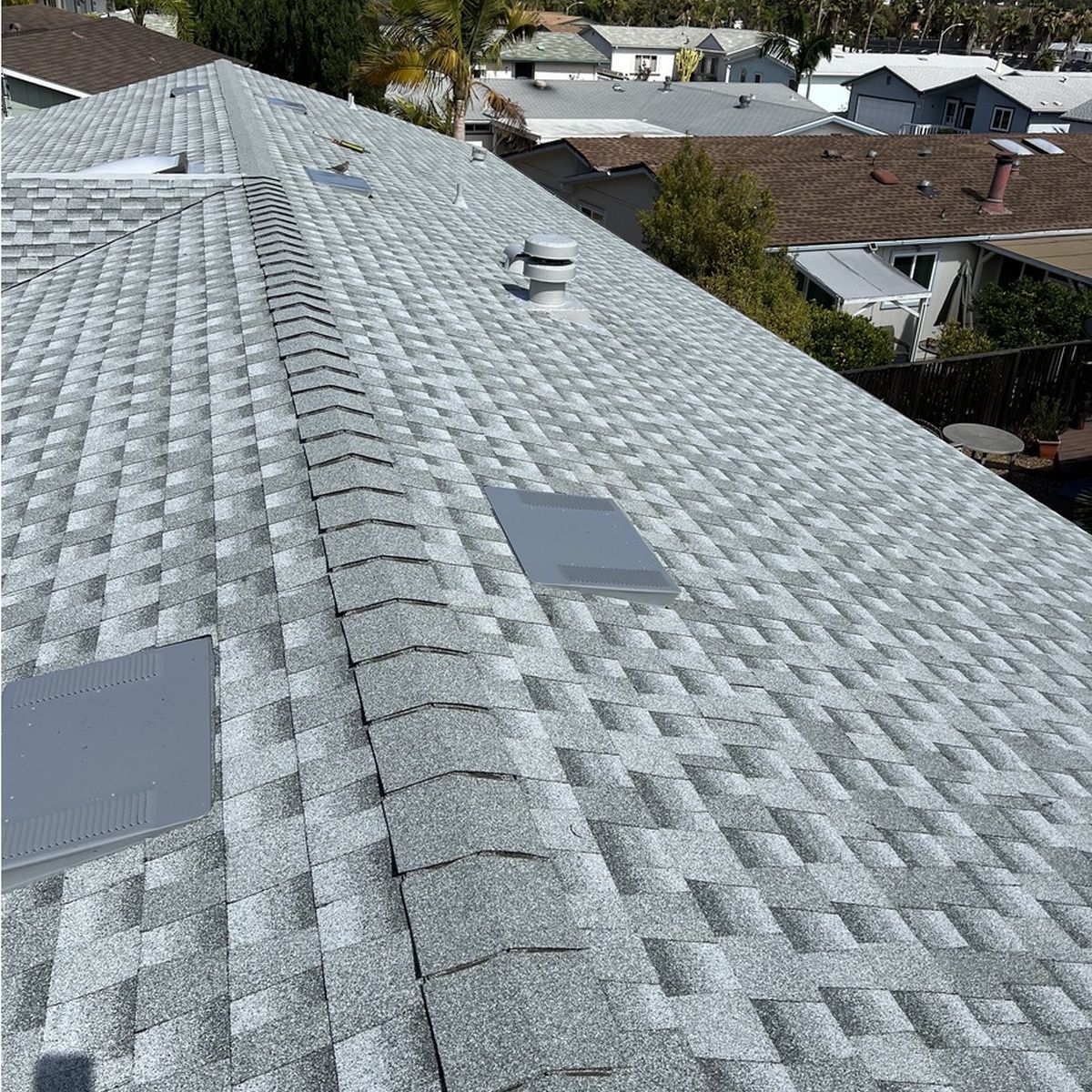 Gray shingled roof with skylights, viewed from above in a suburban neighborhood