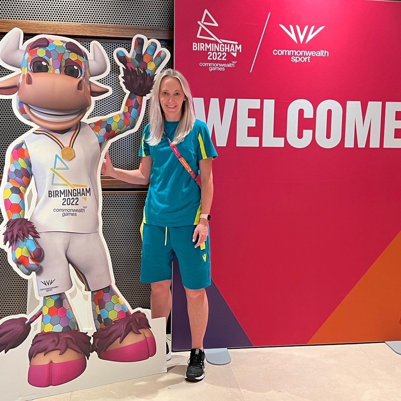 A woman stands in front of a sign that says welcome