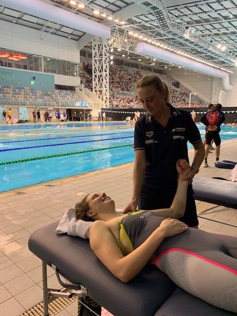 A woman is laying on a massage table in front of a swimming pool