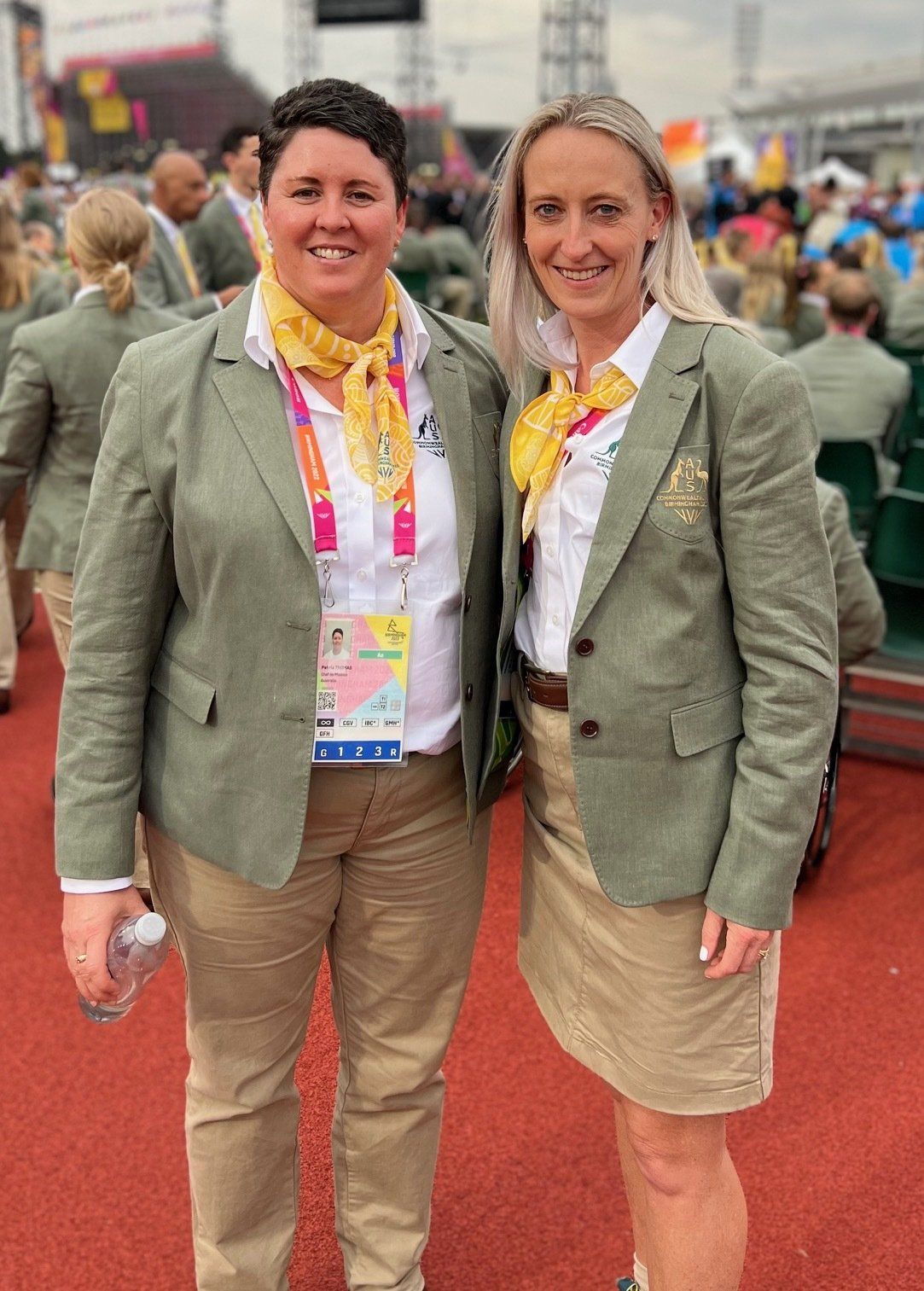 Two women in uniforms are posing for a picture on a track.