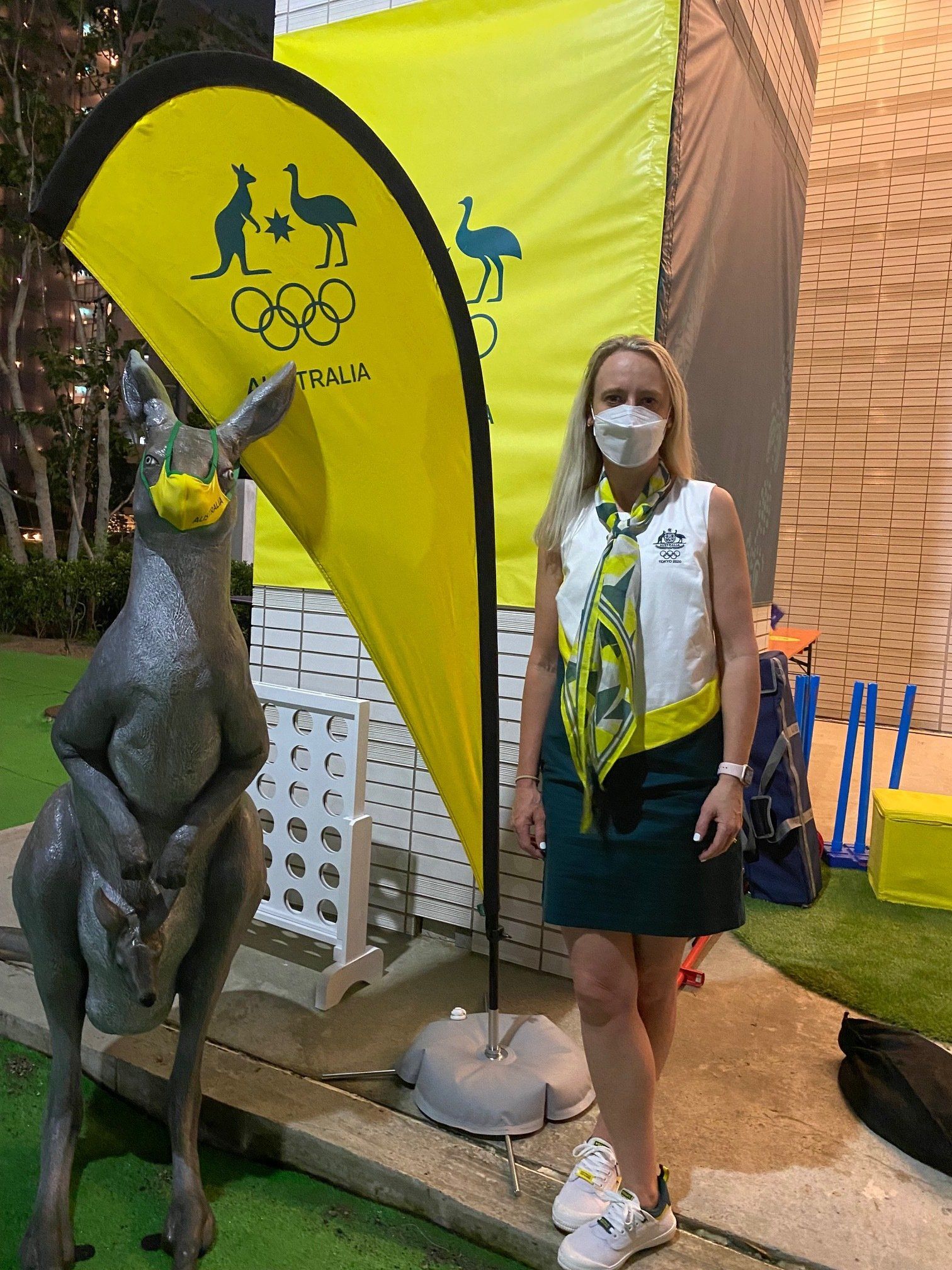 A woman wearing a mask is standing next to a kangaroo statue.