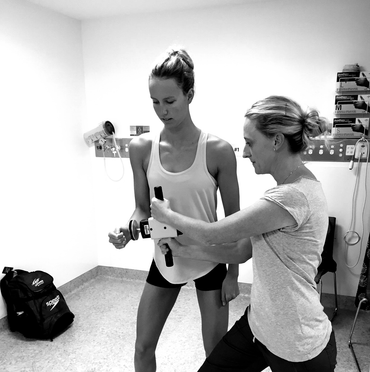 A woman is helping another woman lift a dumbbell