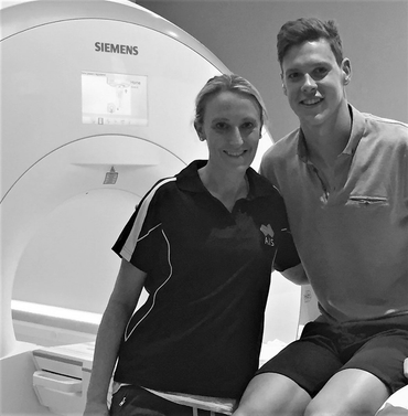 A man and a woman are posing in front of a siemens machine