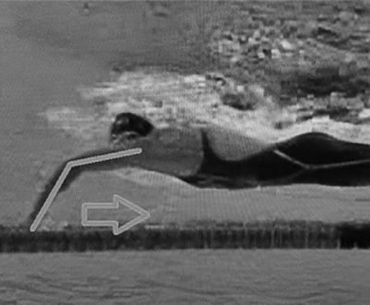 A black and white photo of a person swimming in the water.