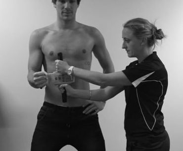 A shirtless man is being measured by a woman