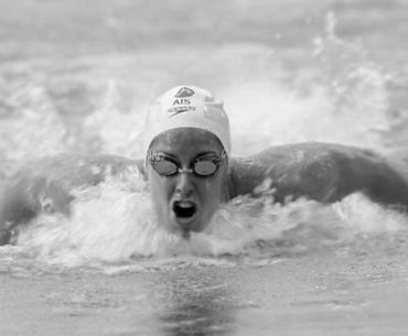 A black and white photo of a woman swimming in the ocean.