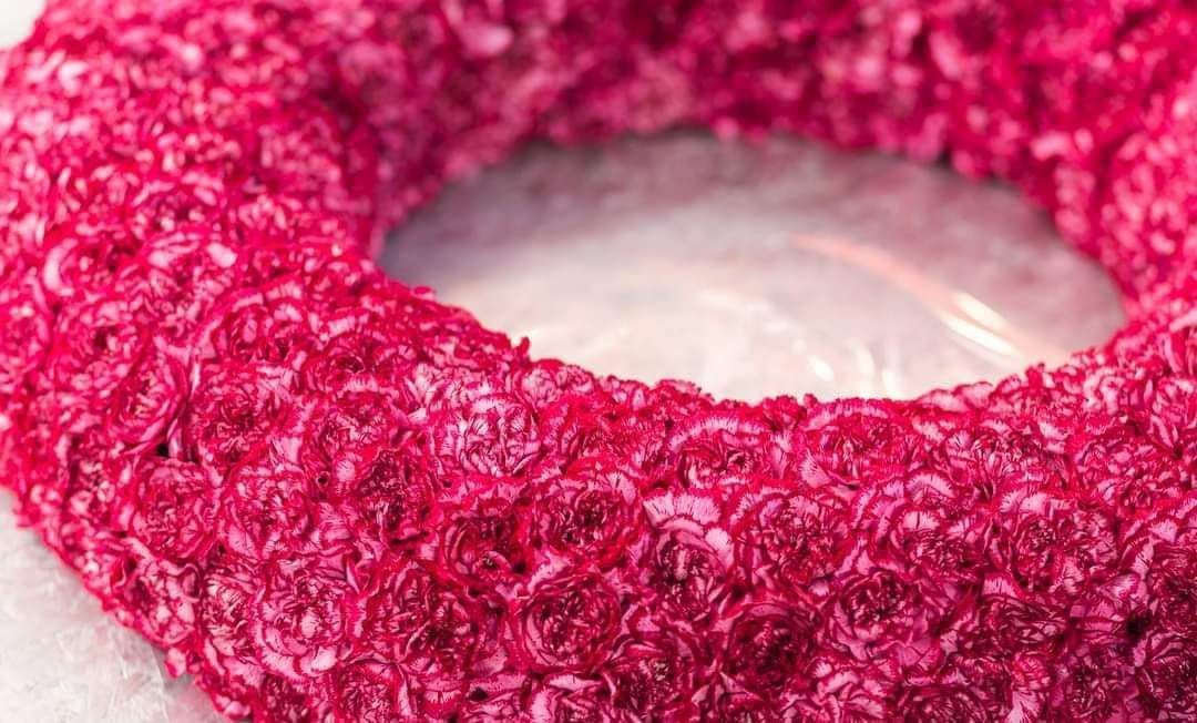 Eine Nahaufnahme eines rosa Kranzes auf einer weißen Oberfläche.