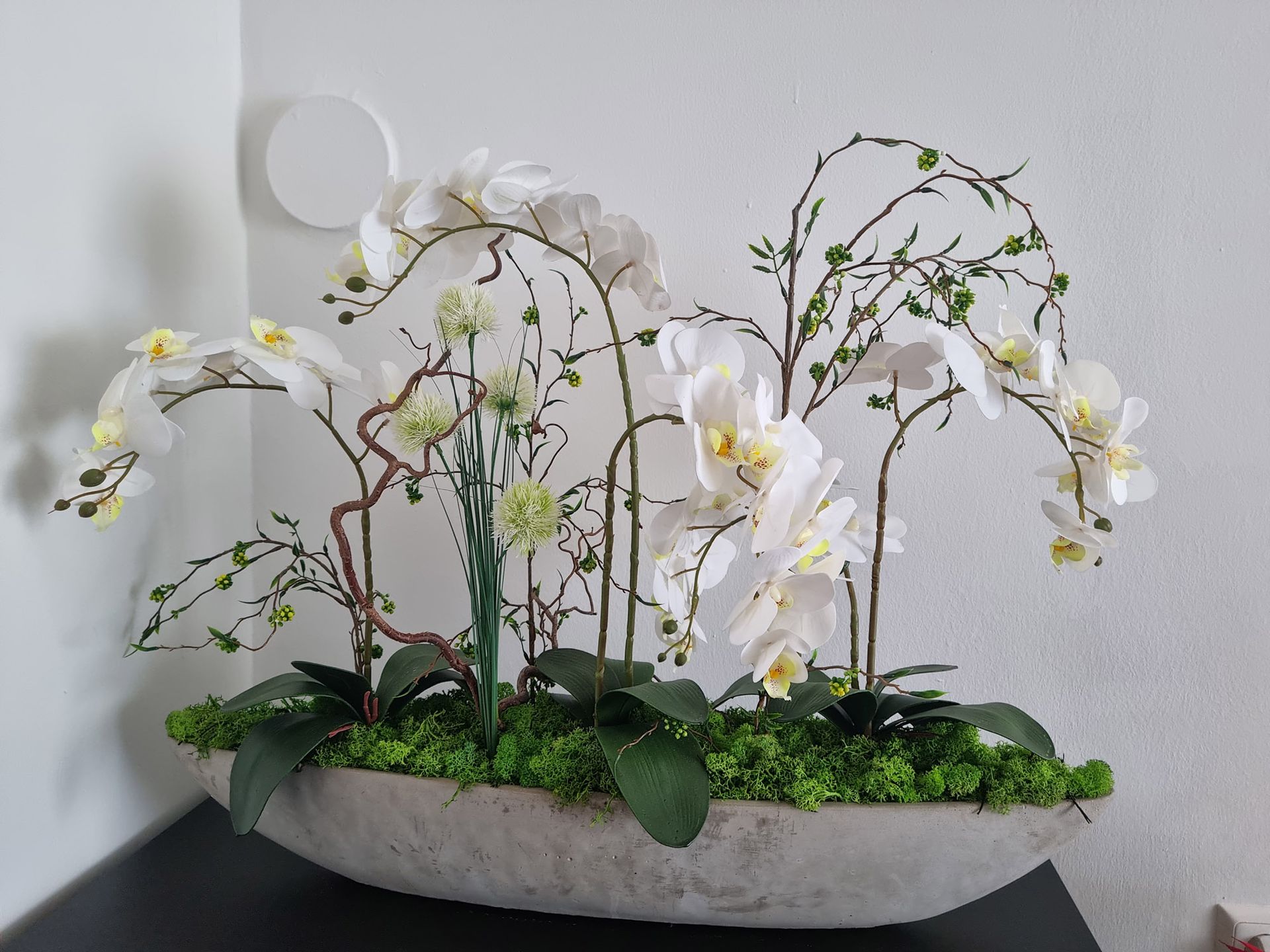 Eine Vase gefüllt mit weißen Orchideen und grünem Moos
