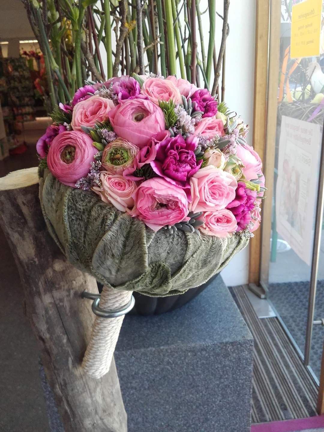 Auf einem Tisch steht eine Vase mit rosa Blumen.