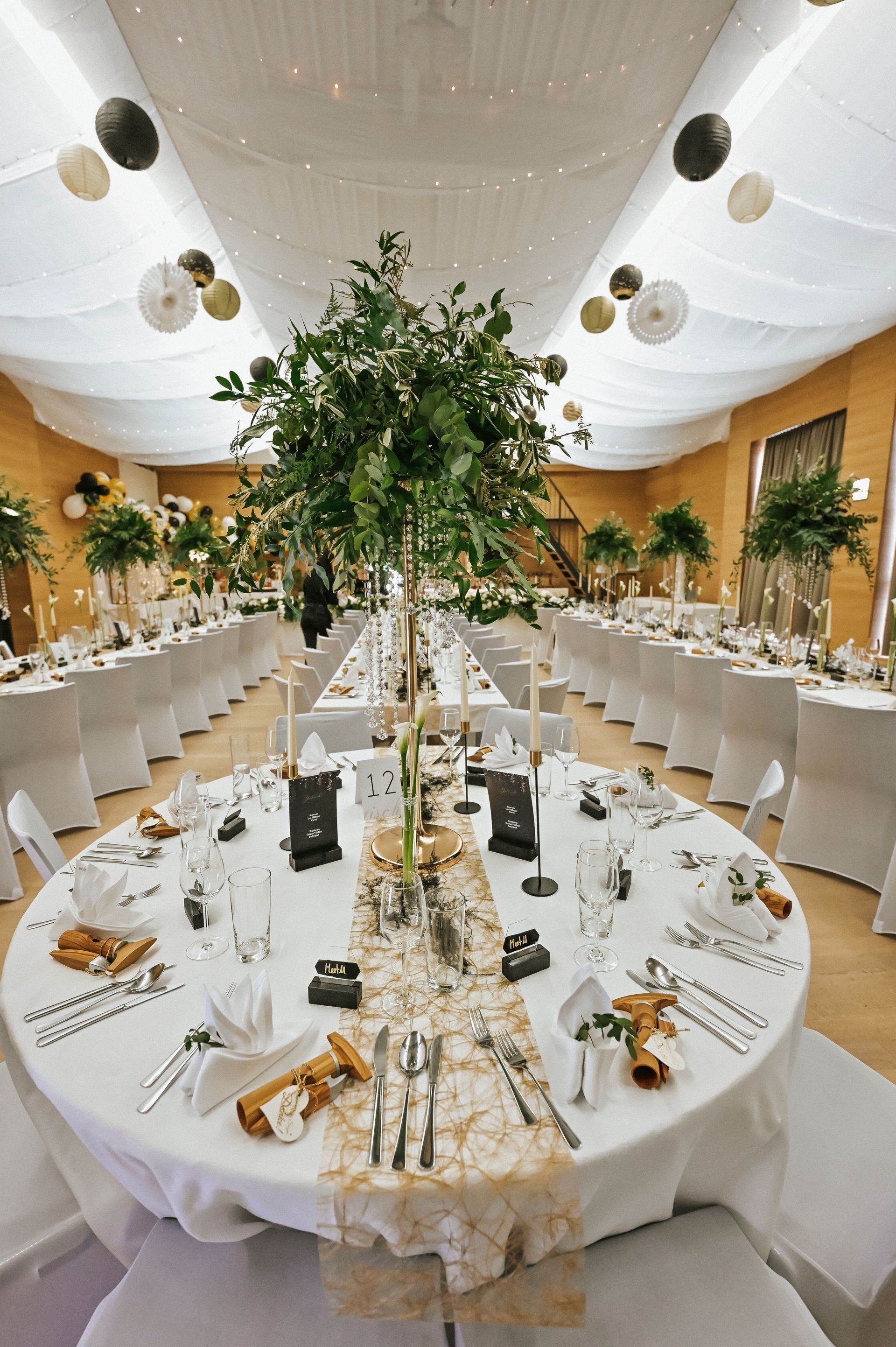 Ein großer Raum mit Tischen und Stühlen für einen Hochzeitsempfang.