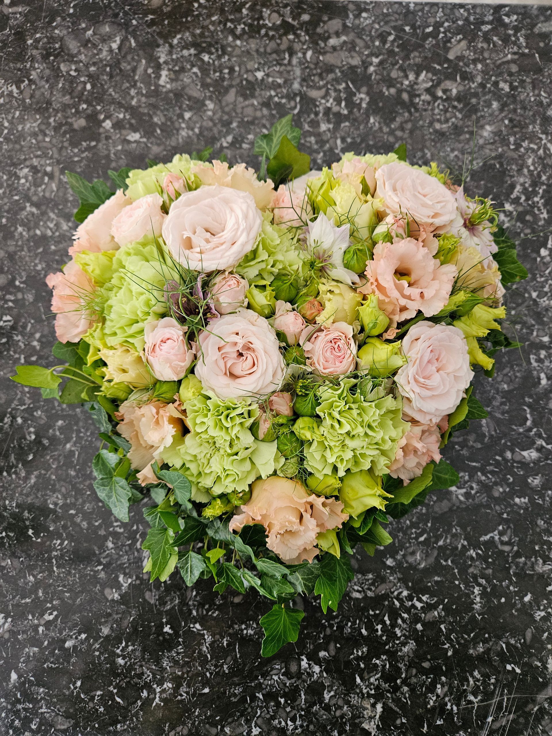 Auf einem Tisch steht ein herzförmiger Blumenstrauß.