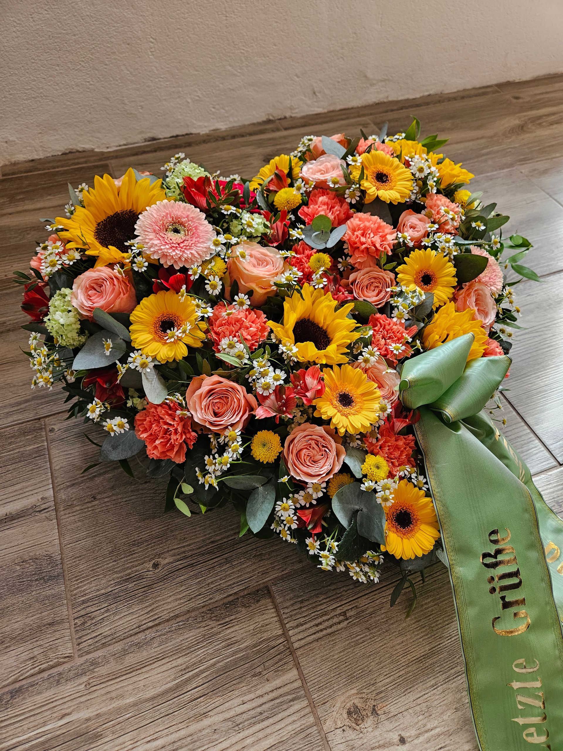 Ein herzförmiger Blumenstrauß mit einer grünen Schleife