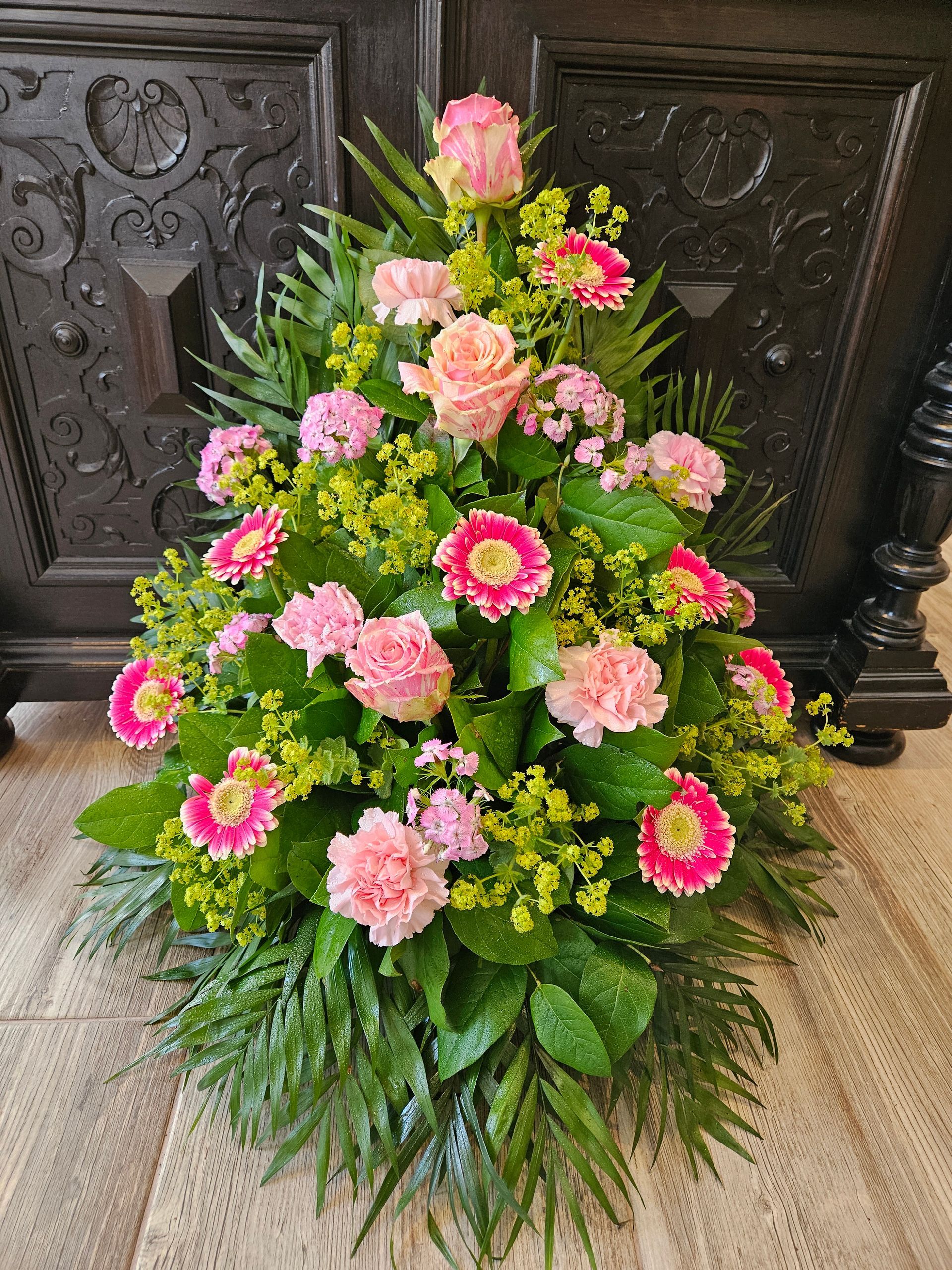 Auf einem Tisch steht ein Strauß rosa und gelber Blumen.