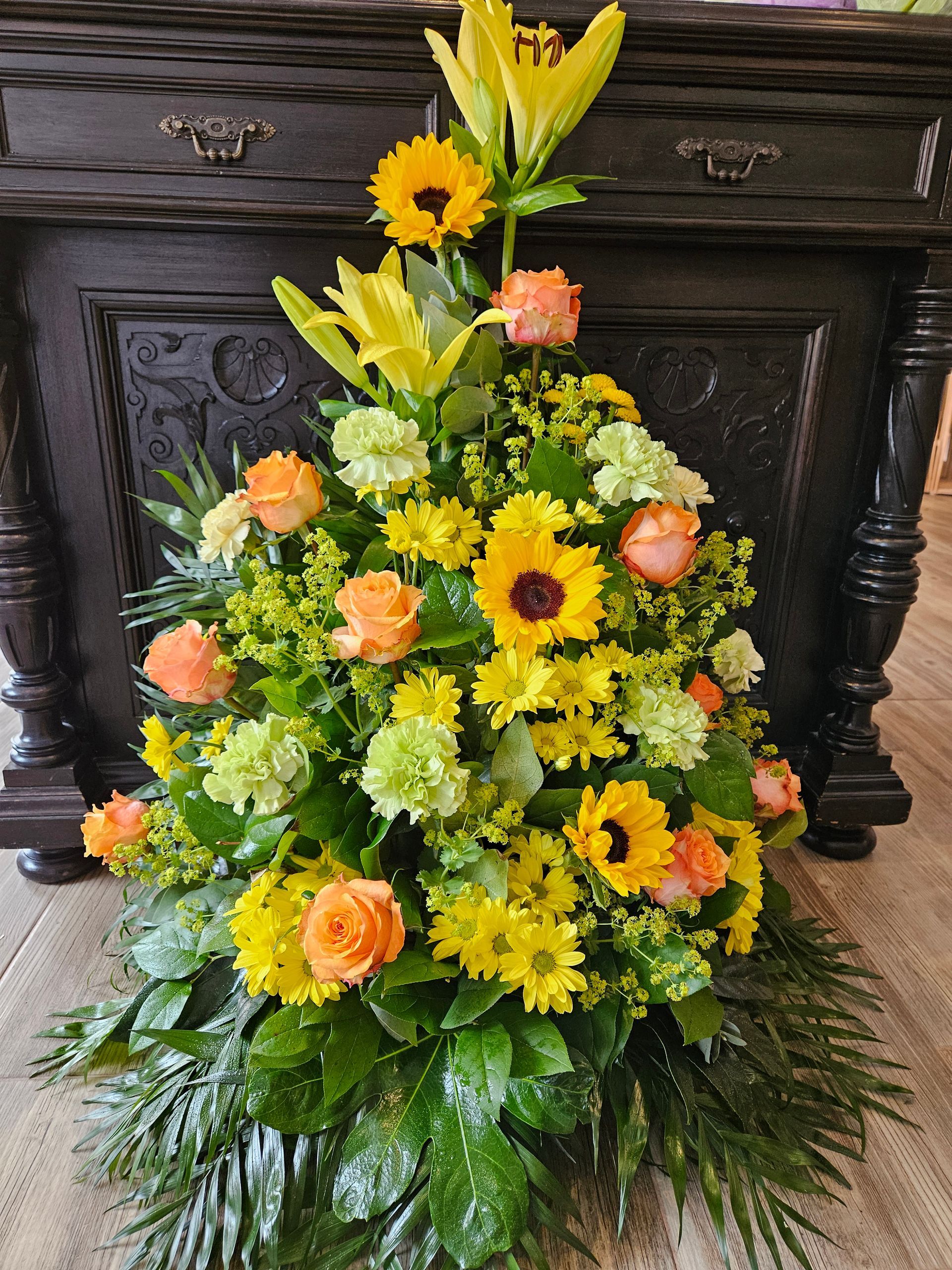 Auf einem Tisch steht ein Strauß gelber und orangefarbener Blumen.