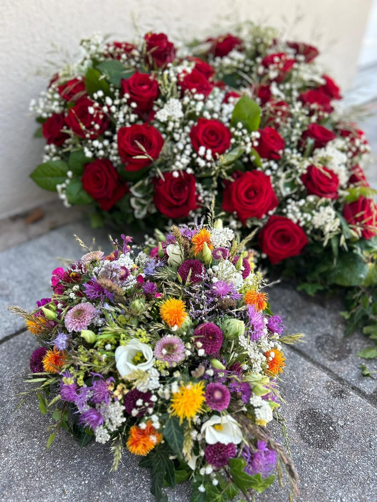 Zwei Blumensträuße stehen nebeneinander auf einem Bürgersteig.