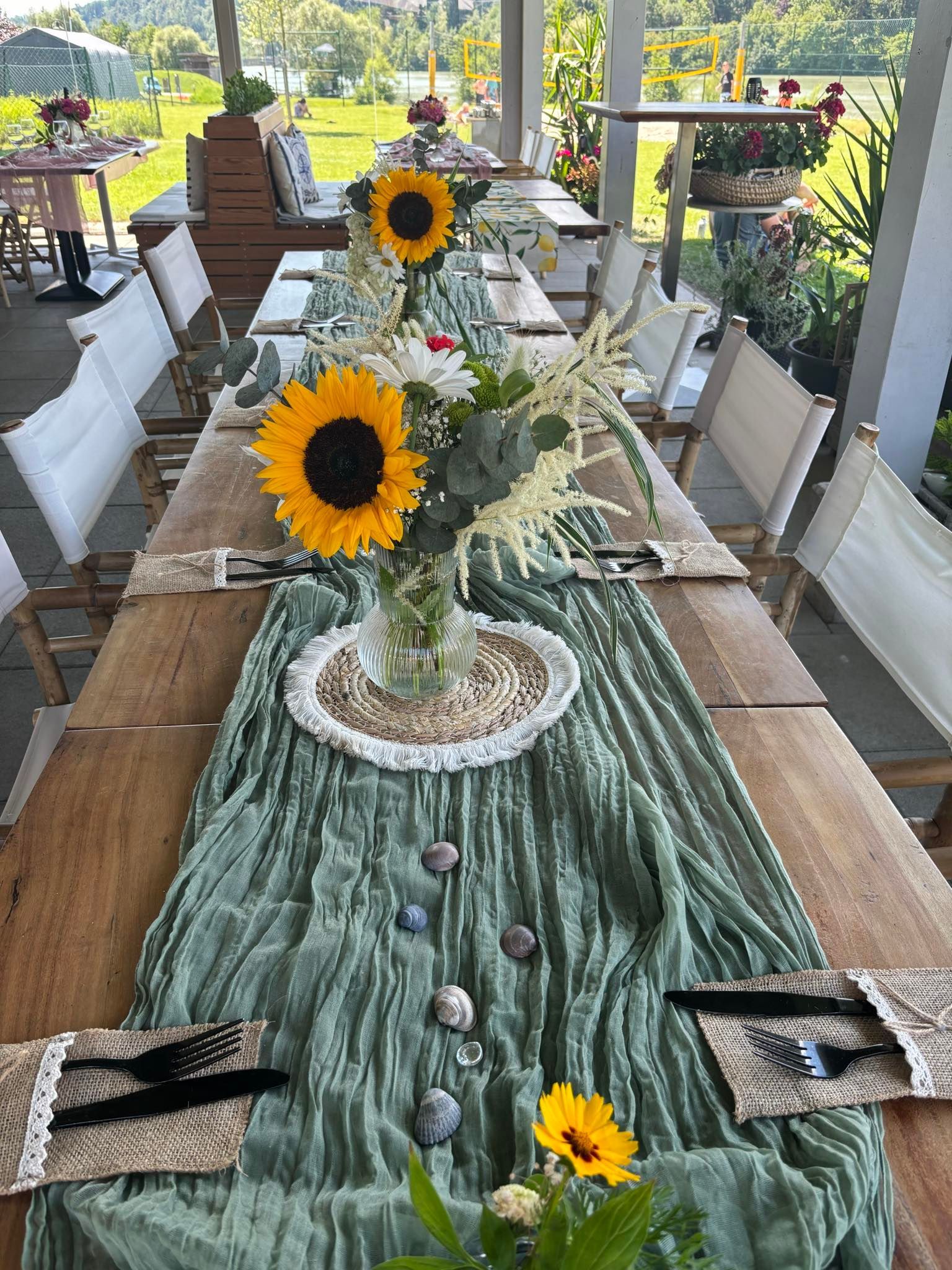 Ein langer Holztisch mit einem grünen Tischläufer und Sonnenblumen darauf.