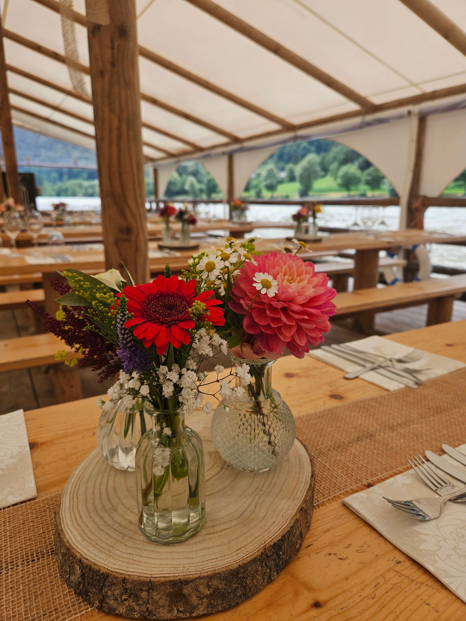 Auf einem Holztisch stehen zwei mit Blumen gefüllte Vasen.