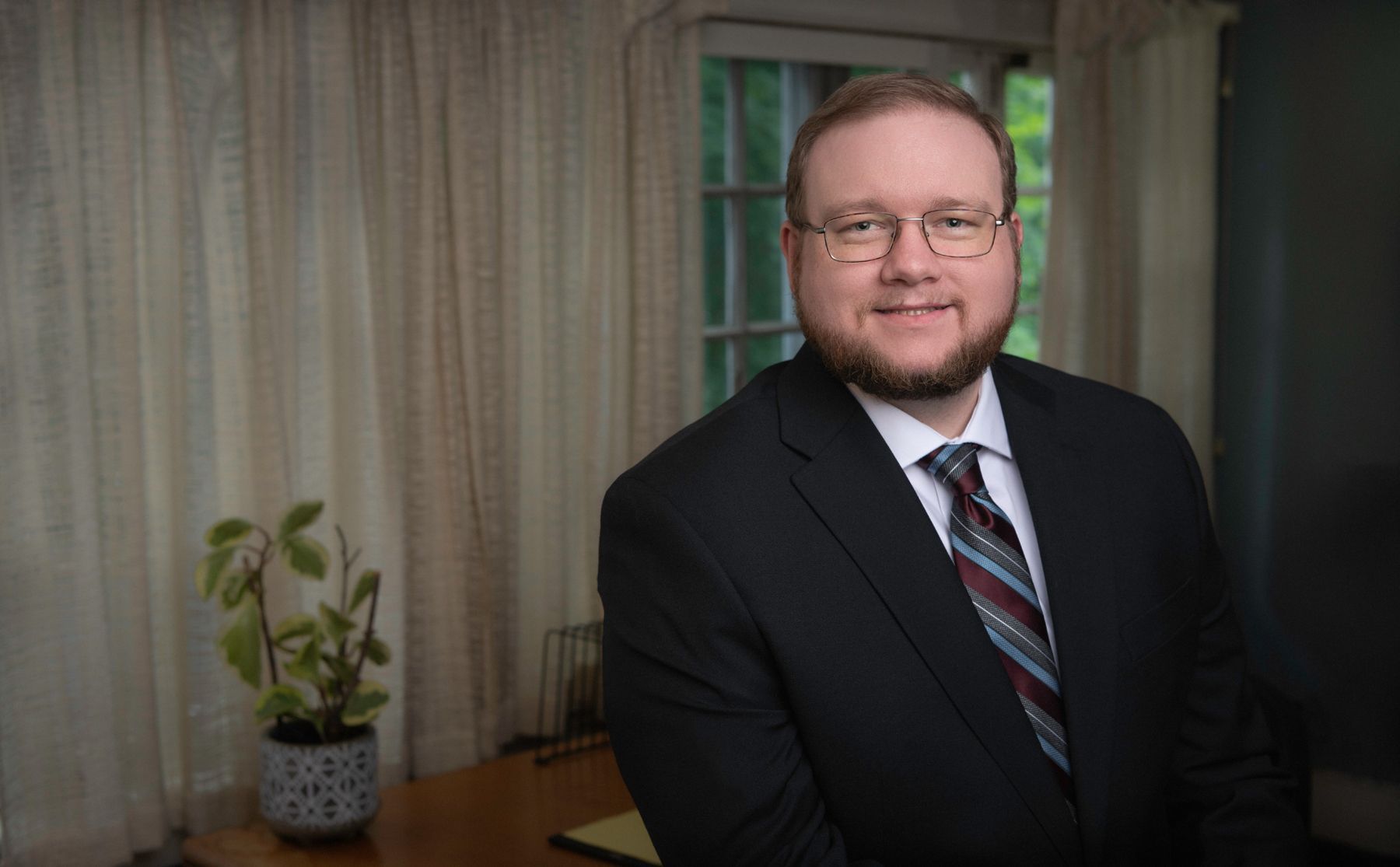 Alexander W. Scott in a suit and tie is sitting at a desk