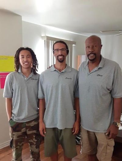 Three men in gray polo shirts stand indoors in a bright room.