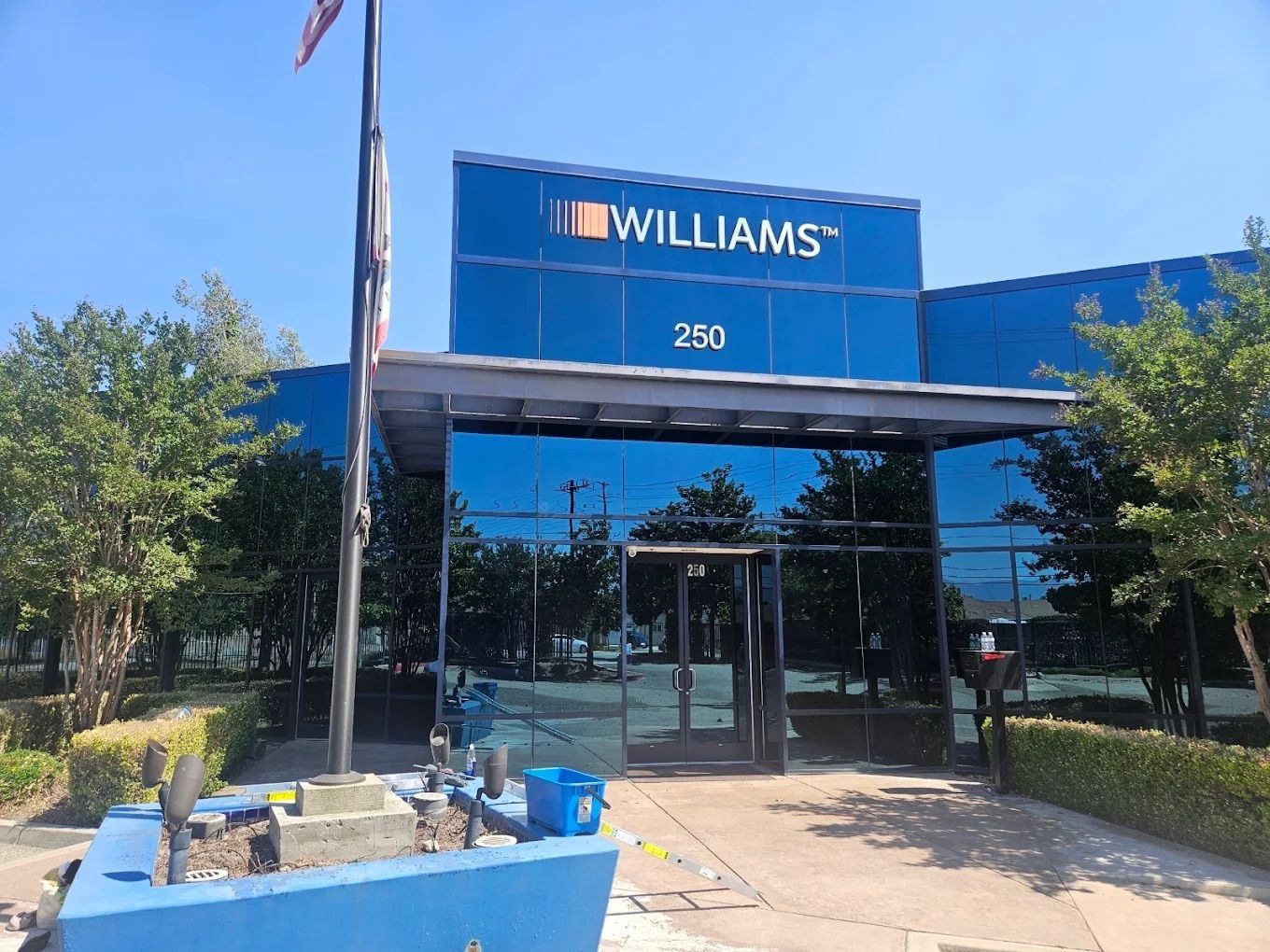 Sunlit glass office building with reflective blue windows and geometric steel lines