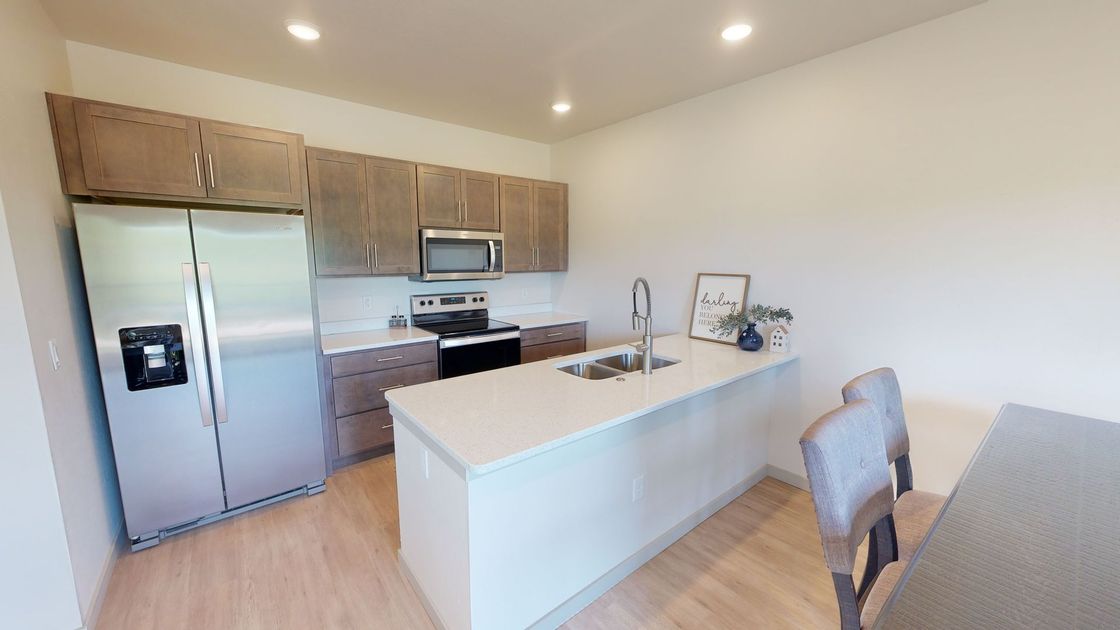 Modern kitchen with island sink, stainless steel appliances, wood cabinets, and white countertops