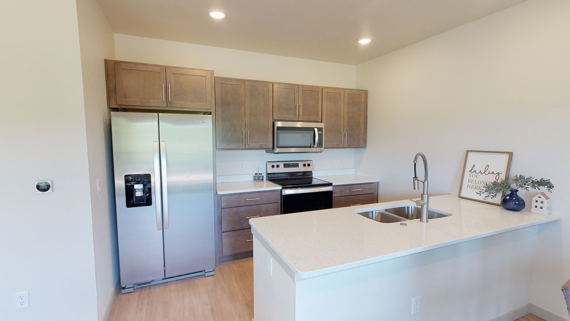 Modern kitchen with stainless steel appliances, wood cabinets, and a white island with sink