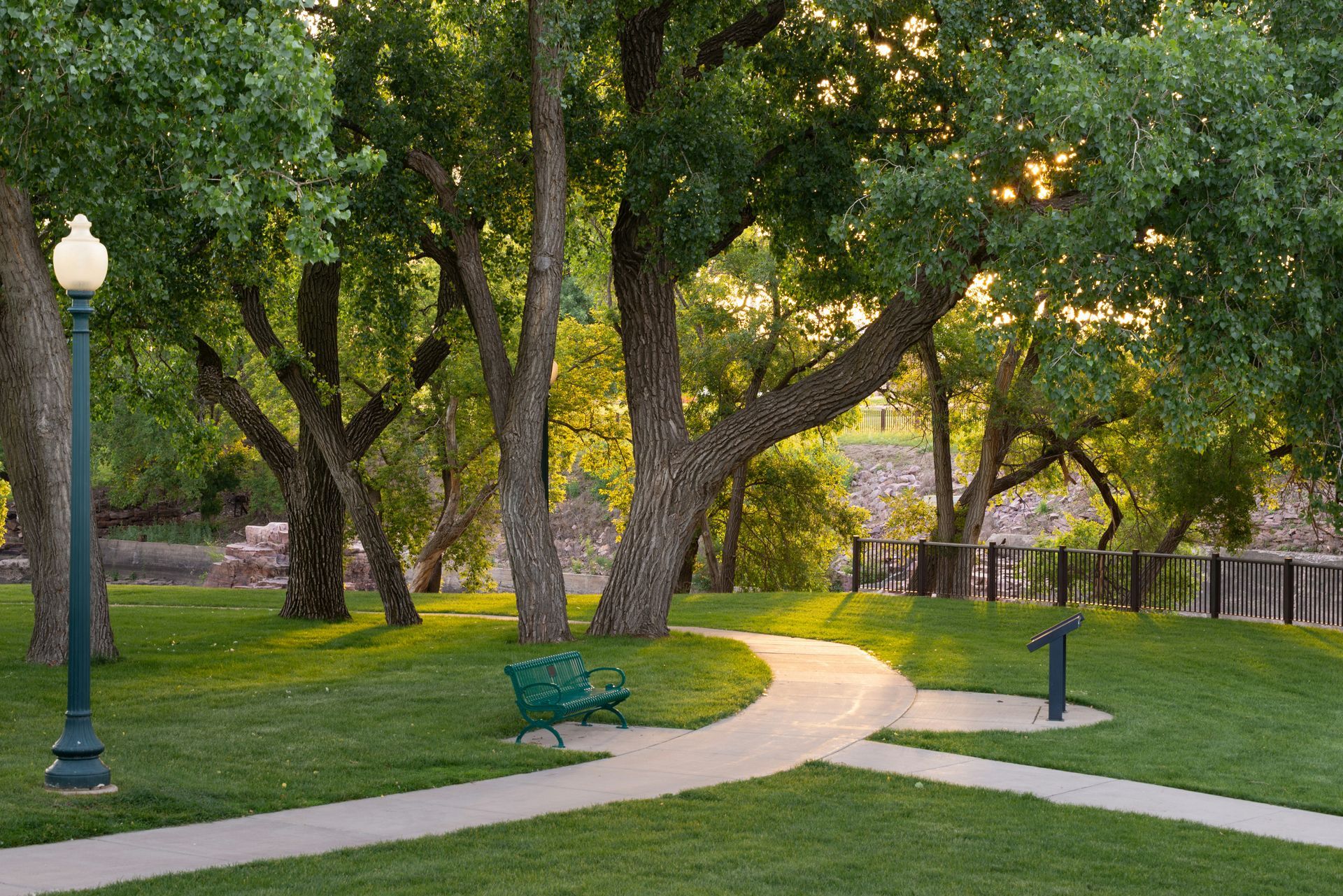 Tree-lined park path with benches and lampposts at dusk
