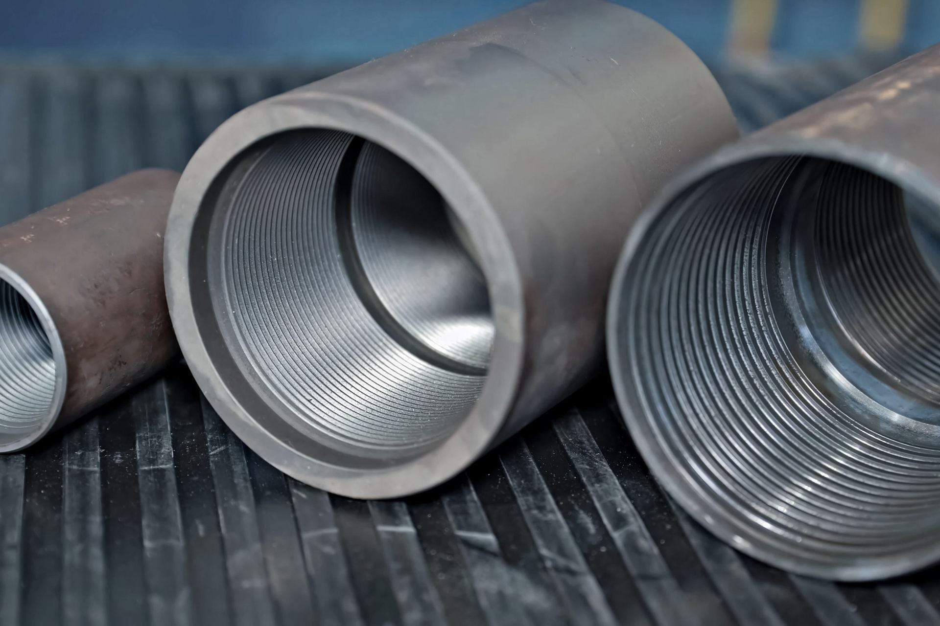 Three gray metal tubes with threaded interior on a dark surface.