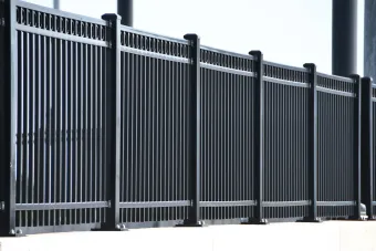 Chain-link fence topped with razor wire against a blue sky with clouds.