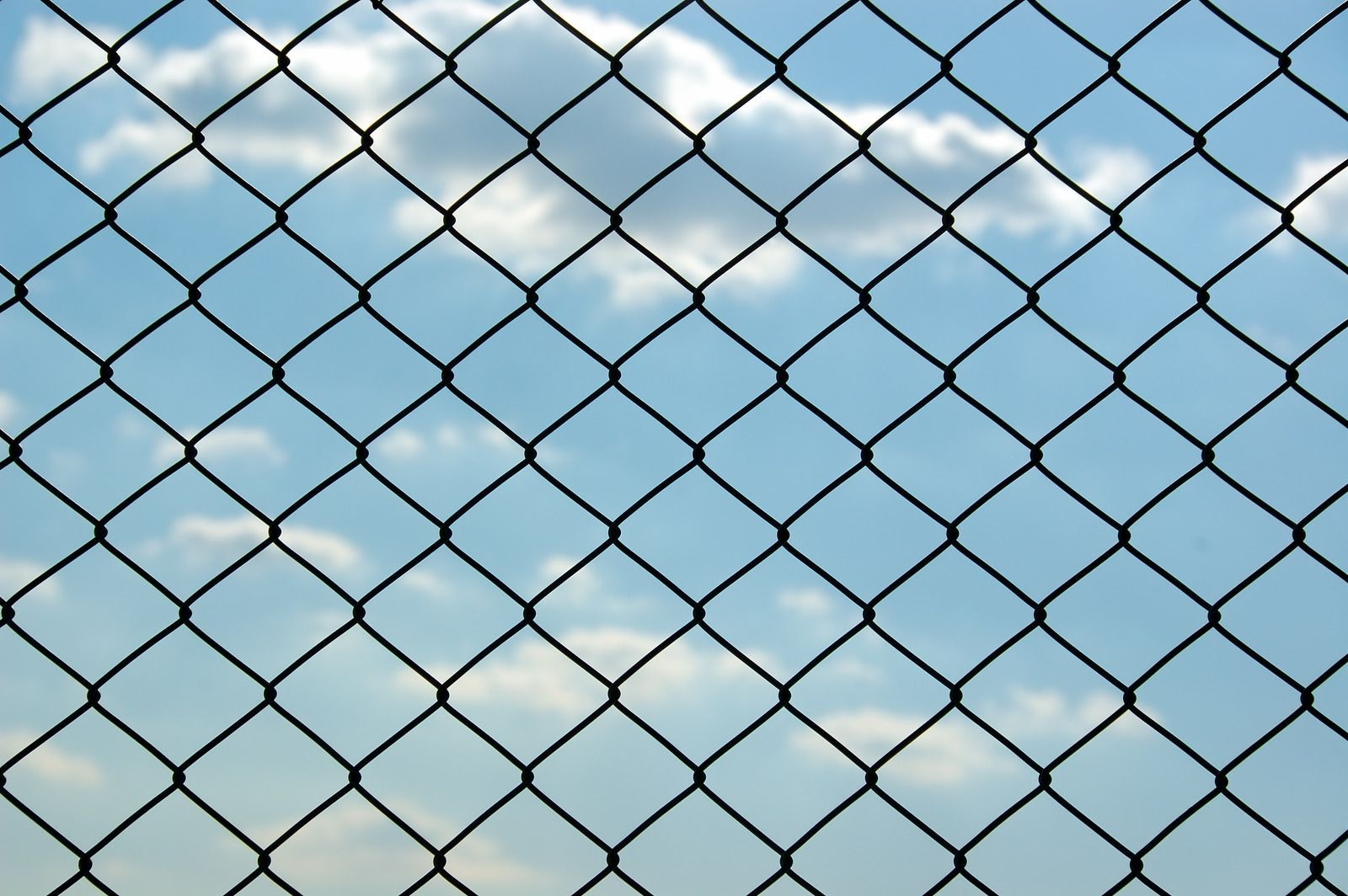Barbed wire fence against a cloudy blue sky.