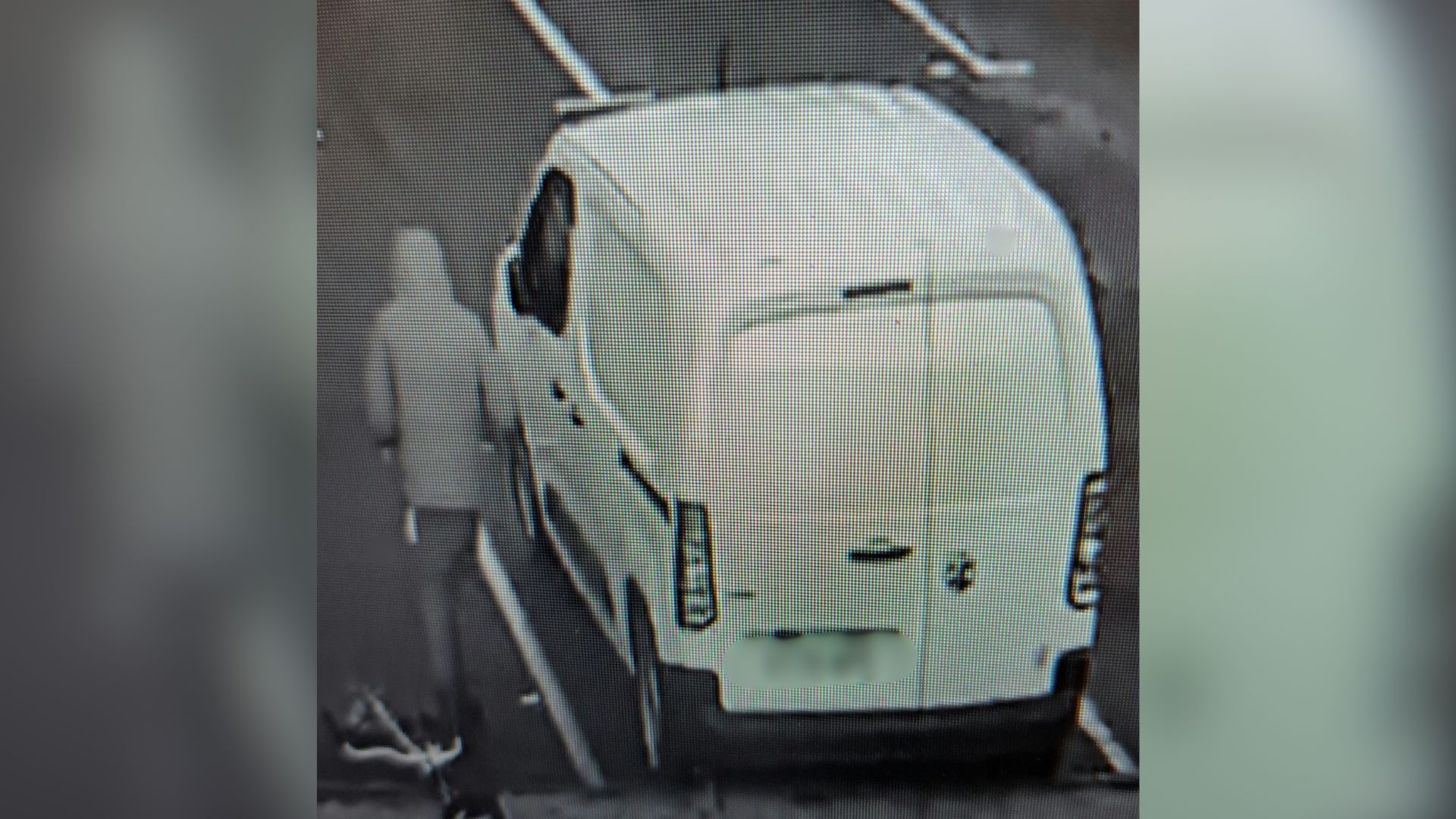 A CCTV image of a thief next to a white van, fleeing the scene of a building.
