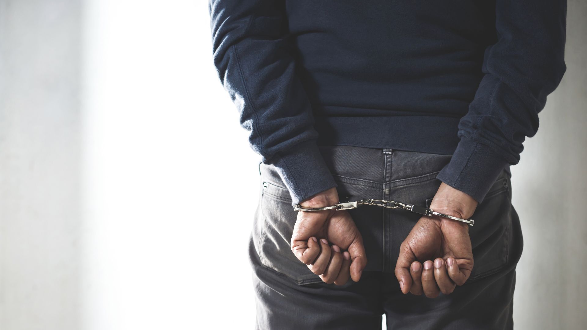 A person with their hands handcuffed behind their back.