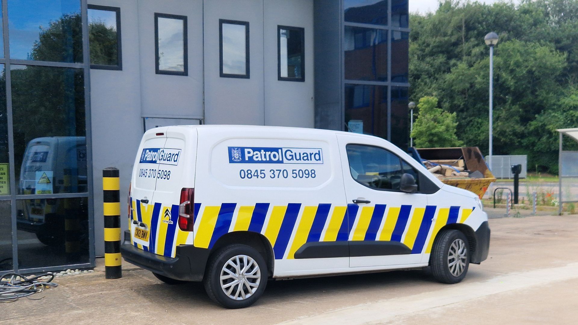 A PatrolGuard van parked outside an industrial building on a sunny day.