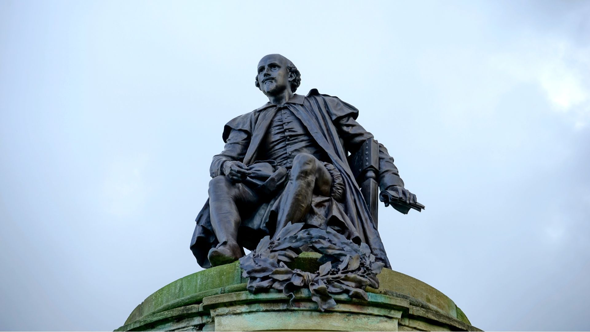 A Shakespeare statue against a clear grey/blue sky.