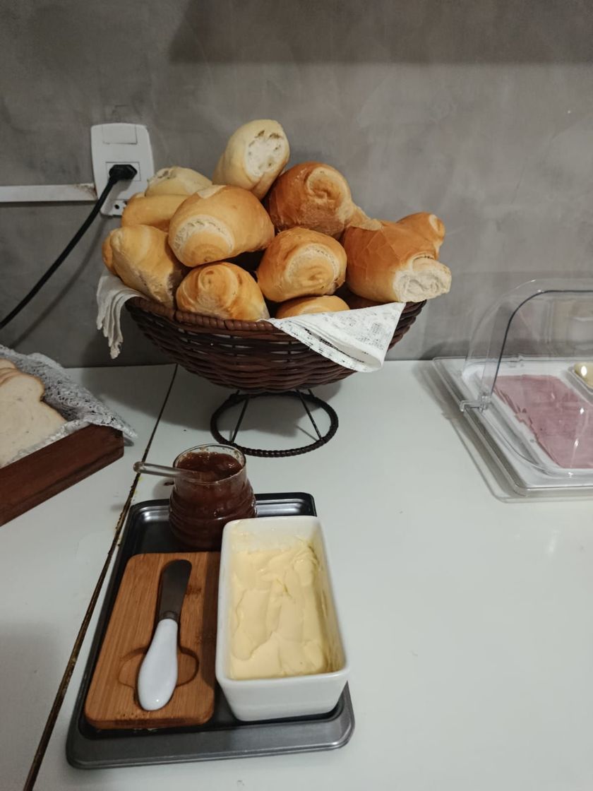 Cesta de pãezinhos em um balcão ao lado de condimentos e espátulas para manteiga.