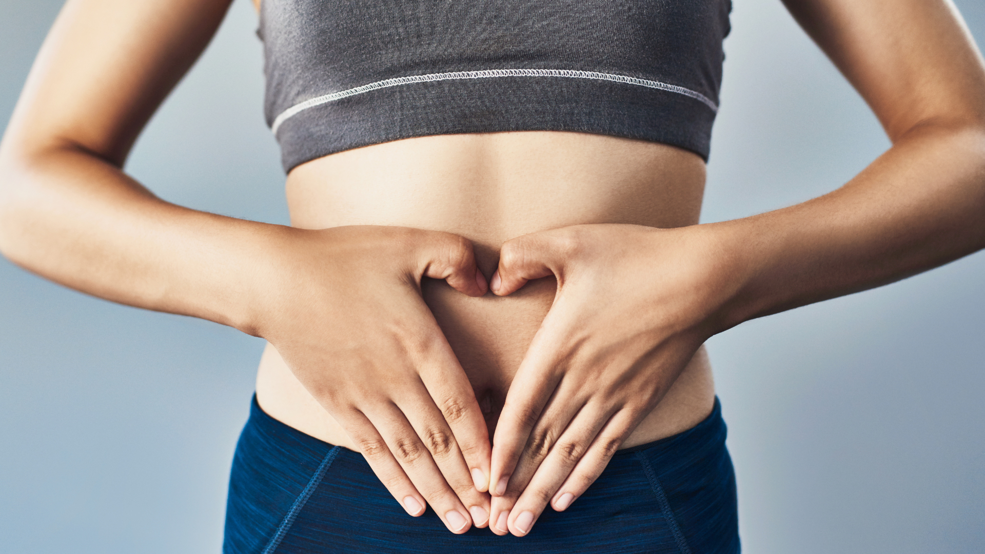 Person forms heart with hands over abdomen.