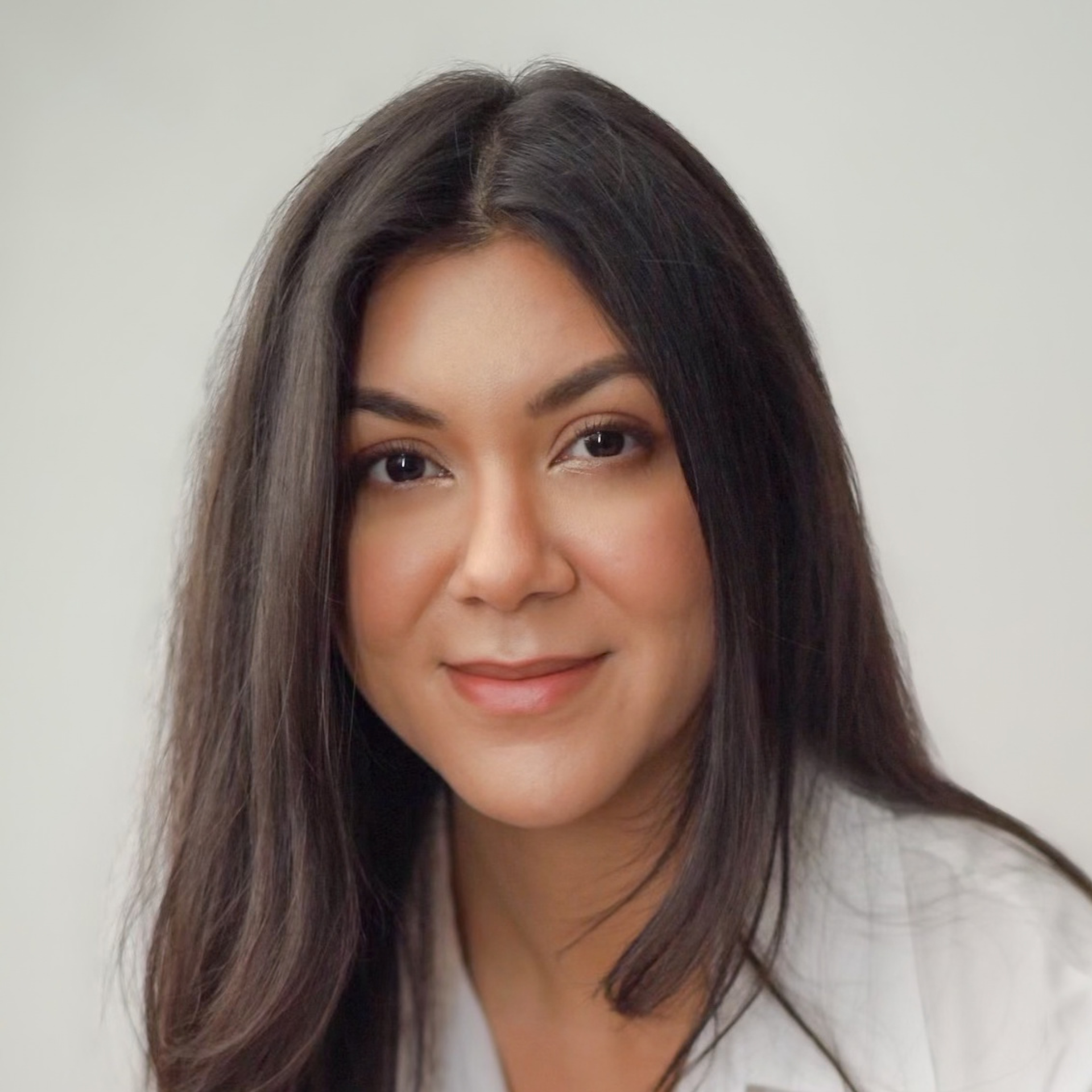 Portrait of a smiling person with long dark hair against a light background