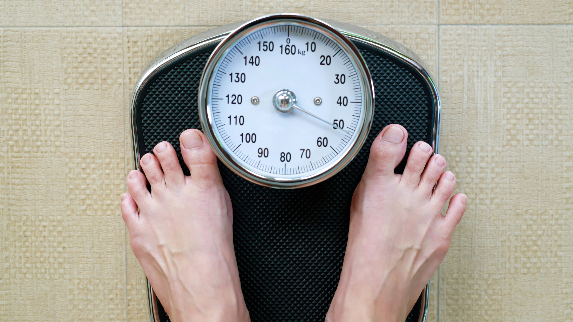 Feet standing on a bathroom scale, pointer indicating weight.