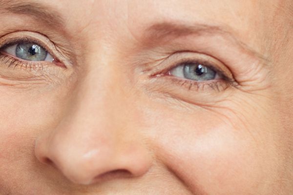 A close up of a woman 's face with blue eyes and wrinkles.