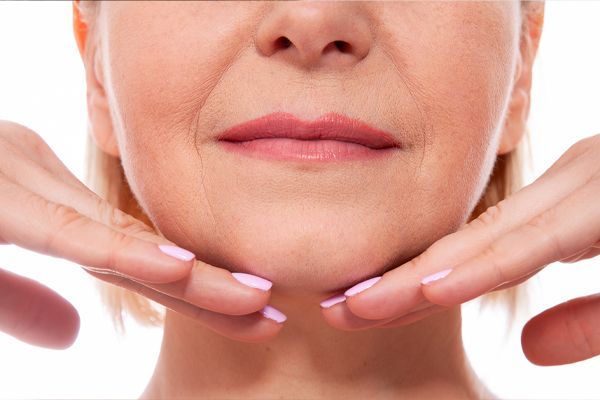 A woman is touching her chin with her hands.