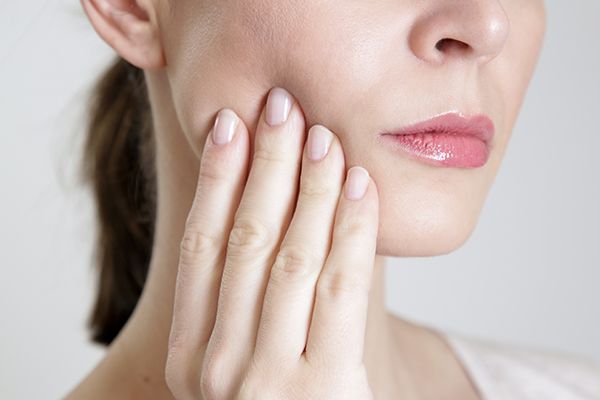 A woman is holding her face in pain because of a toothache.
