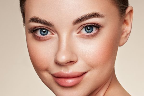 A close up of a woman 's face with blue eyes and pink lips.