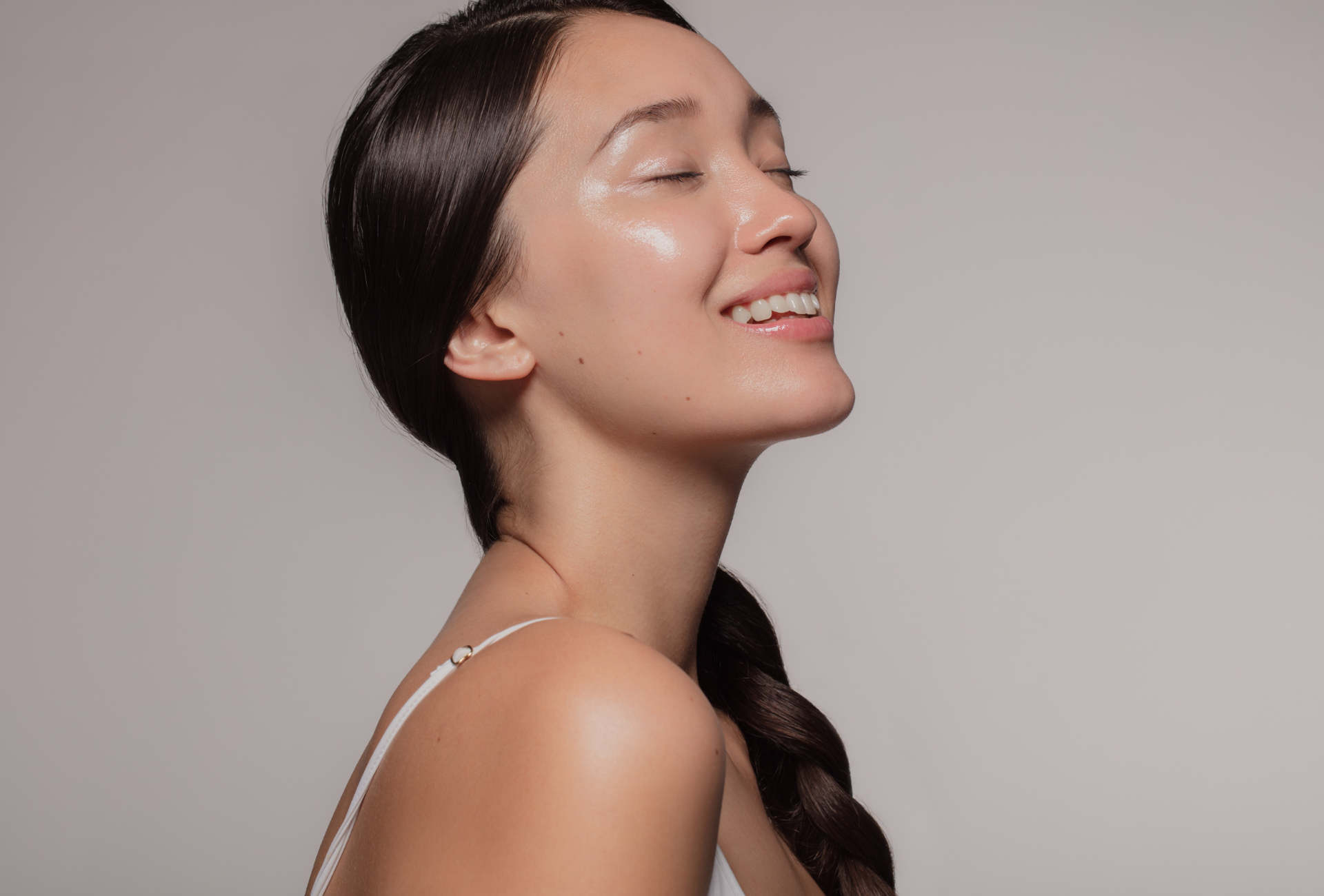 A woman is smiling with her eyes closed and her hair in a braid.